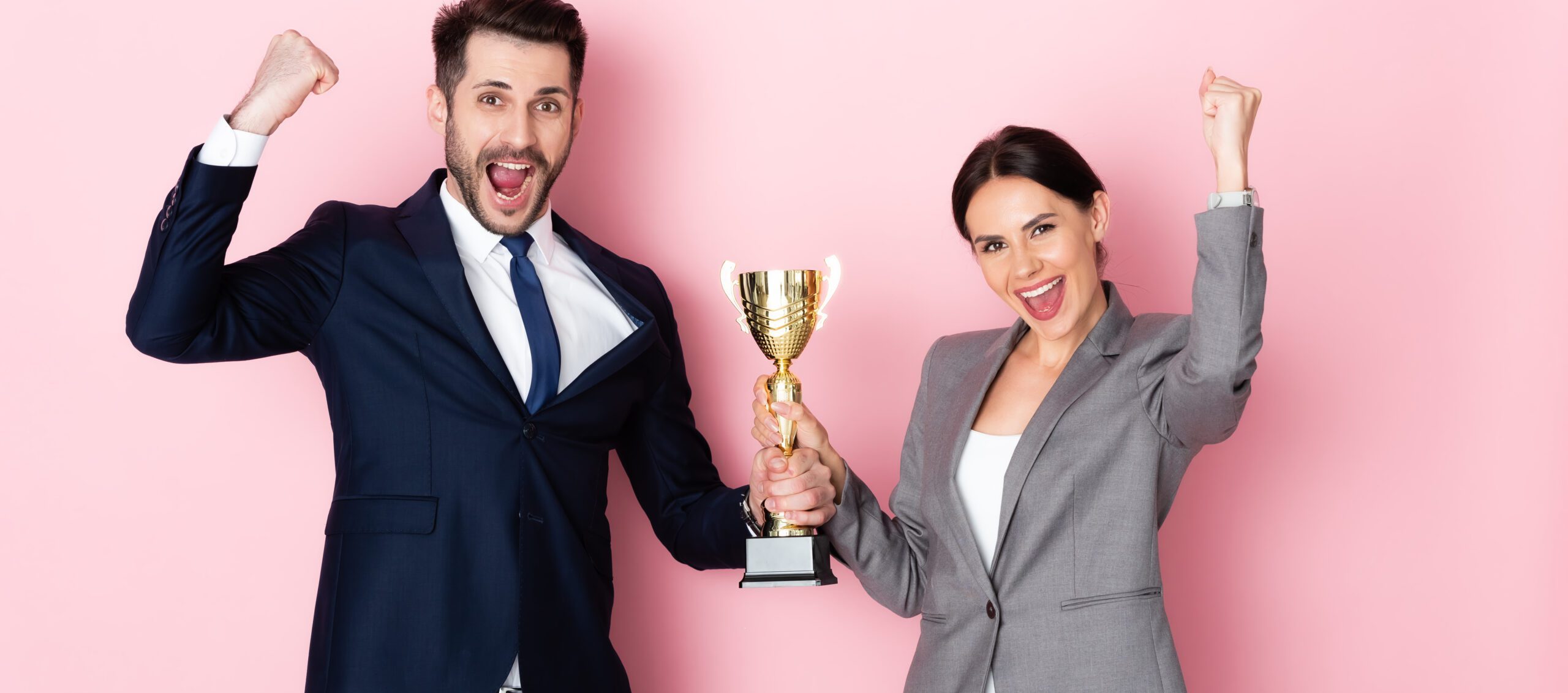 Un homme et une femme devant un fon rose qui porte un trophée en souriant